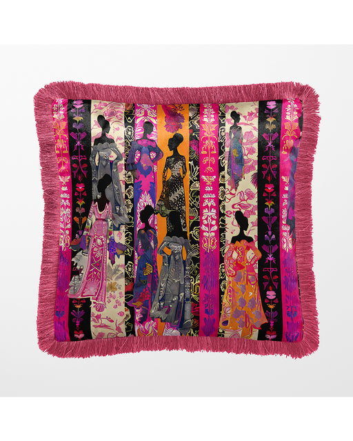Decorative velvet luxury pillow in an eclectic bohemian style featuring silhouettes of women in vibrant, patterned dresses against vertical stripes in pink, orange, purple, and black. The pillow is bordered with a pink fringe.