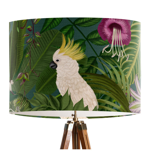 Parrots in white, green & blue along with monkeys sit amoungst green tropical leaves and pink flowers on a classic sized 30x21cm handcrafted fabric lampshade by artist Kelly Stevens-McLaughlan