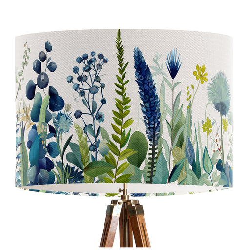 A stylish floral and grass design in harmonious shades of blue and green on a pristine white background on a classic sized 30x21cm handcrafted fabric lampshade by artist Kelly Stevens-McLaughlan