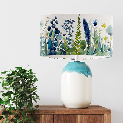 A stylish floral and grass design in harmonious shades of blue and green on a pristine white background on a Extra large sized 45x25cm handcrafted fabric lampshade by artist Kelly Stevens-McLaughlan