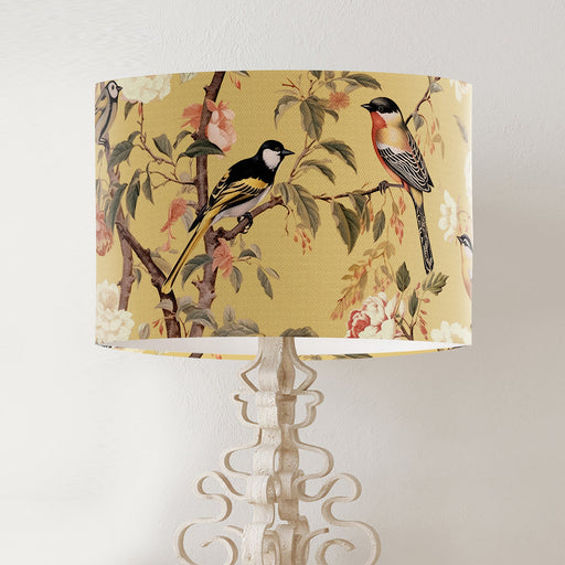 Pink and peach flowers and country garden birds on branches on a soft warm yellow background on a classic sized 30x21cm handcrafted fabric lampshade by artist Kelly Stevens-McLaughlan
